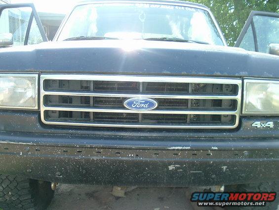Front of a dark-colored Ford truck with doors open. Grille has a Ford logo. 4x4 badge visible on the right