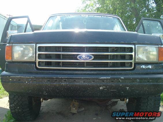 Black Ford truck front view, grille and headlights visible, doors open, 4x4 badge on fender