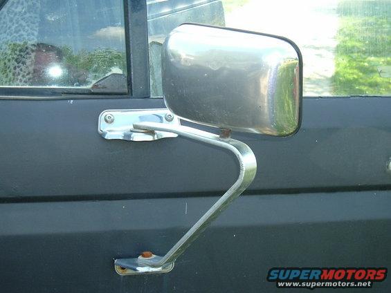 Chrome side mirror on dark door panel, with reflection in window