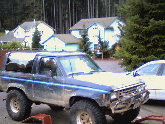 Blue Ford Bronco II with off-road tires and a brush guard
