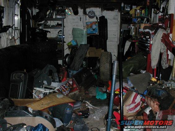 Cluttered garage interior with shelves, tires, and tools