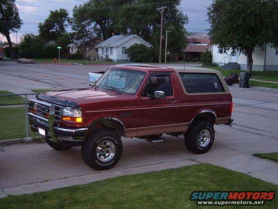 Red 1994 Ford Bronco with tan top parked on driveway