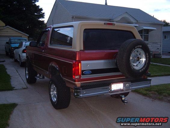 Red and tan Ford Bronco with a spare tire mounted on the rear, parked in a driveway