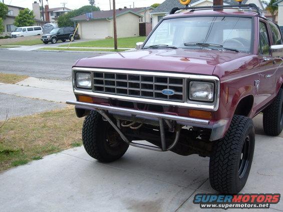 Maroon Ford Bronco II with aftermarket bumper and roof rack. Parked on a driveway