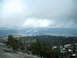 1989 Ford Bronco - Overcast sky above a vast mountain range covered in pine trees and scattered snow.