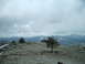 1989 Ford Bronco - Vehicles are parked on a high, rocky terrain with expansive mountain views and a cloudy sky.