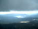 1989 Ford Bronco - A vast landscape of mountains and a lake is visible under a heavy cloud cover.