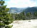 1989 Ford Bronco - A scenic view of snow-capped mountains and pine forests under a partly cloudy sky.