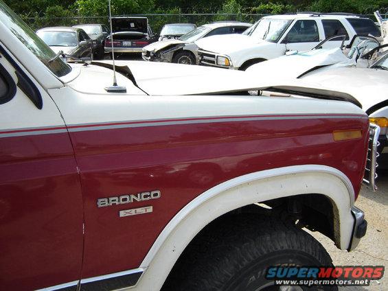 1986 Ford Bronco XLT with damaged hood, parked in a lot with other vehicles