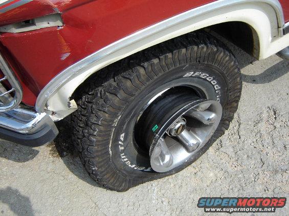 Flat tire on a red and white vehicle, showing the rim and BFGoodrich All-Terrain T/A tire