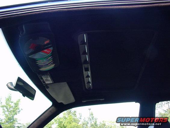 Car interior ceiling with a CD holder filled with discs, a sunroof, and a rearview mirror