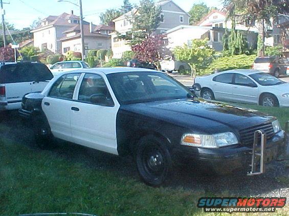 Black and white sedan parked on grass. Another white car is behind it