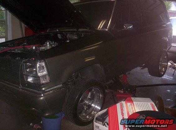 Dark green 1989 Ford Bronco II with hood open, being worked on in a garage
