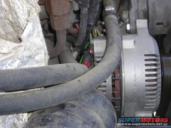 Close-up of an alternator with hoses and engine components. Text on a hose reads 'HEATER HOSE 5/8"'