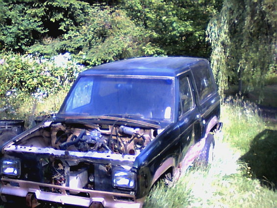 1987 Ford Bronco II, hood open, parked in grassy area with trees in background