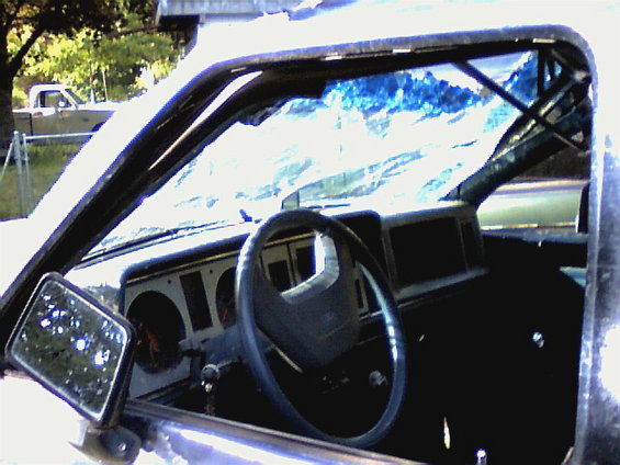 Interior of an older SUV, showing dashboard, steering wheel, and side mirror