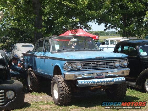 Light blue classic Ford sedan with huge tires, black roof, and a shark-tooth pattern on the front bumper. Ford Trucks badge visible