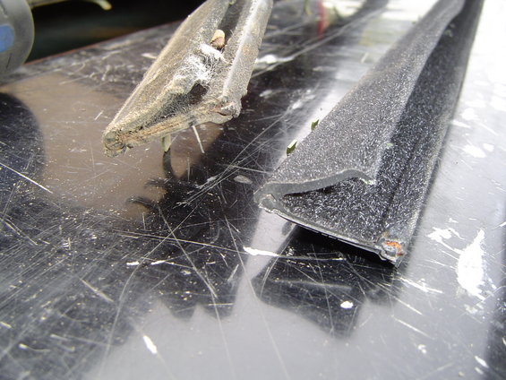 Close-up of two pieces of worn rubber window seal on a scratched surface