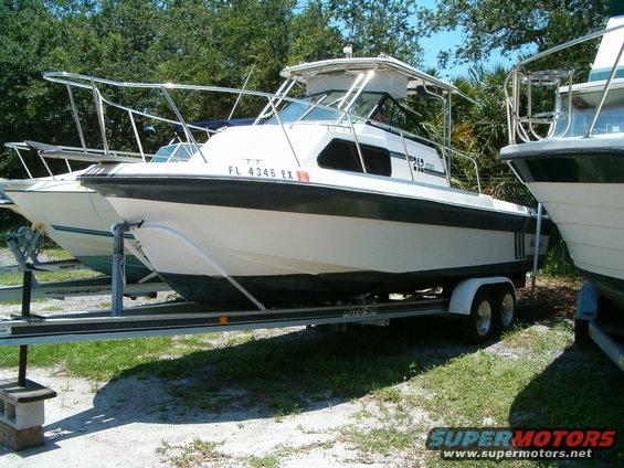 White cabin cruiser boat on trailer, parked outdoors next to another boat