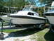 1991 Ford Bronco - A white cabin cruiser boat is seen on a trailer, parked outside next to another vessel.