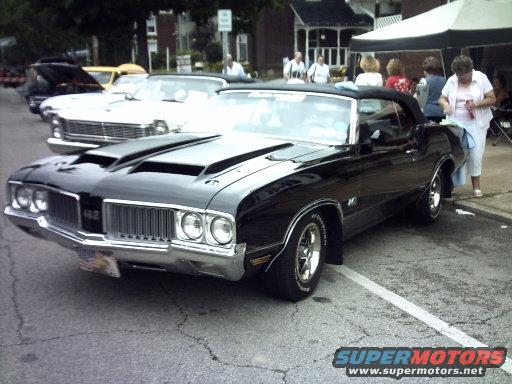 Black convertible with dual hood scoops and chrome grille parked on street