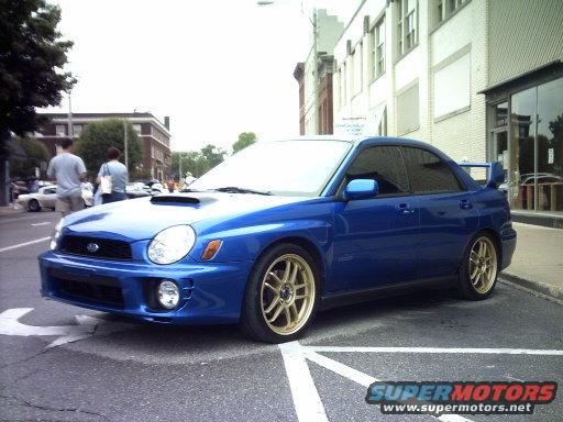 Blue Subaru Impreza WRX with gold wheels parked on street