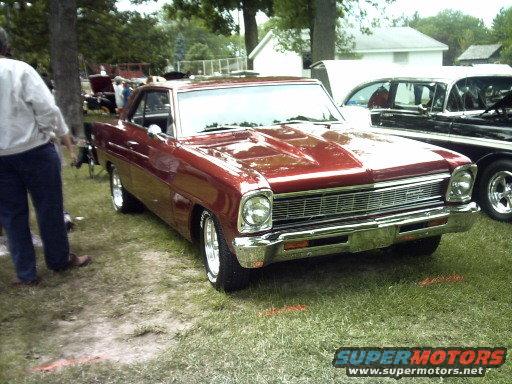 Red 1966 Chevrolet Nova parked on grass, front 3/4 view