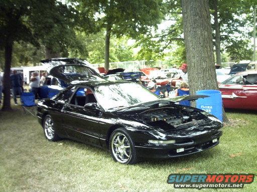 Black 1995 Ford Probe with hood open, parked on grass