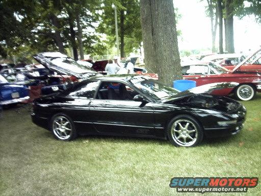 1995 Ford Probe coupe with hood open, parked on grass at a car show with other vehicles