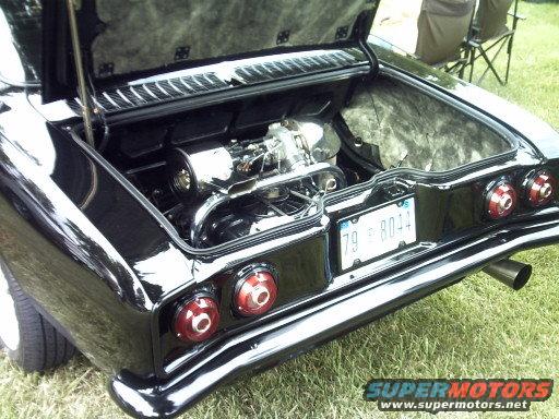 Rear view of a black classic car with trunk open showing engine, license plate reads 79-8044