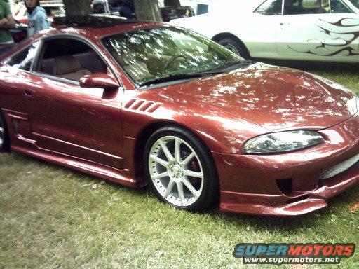 Red coupe with aftermarket body kit and custom wheels, 3q-front view