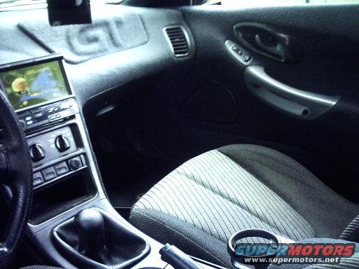 Interior shot of a car, showing dashboard, center console with gear shift, and passenger seat. A GPS screen is visible