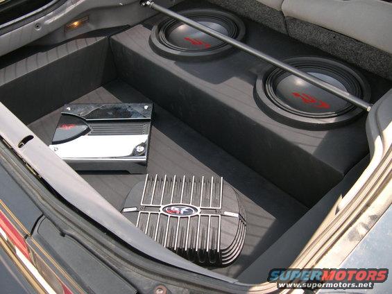 Car trunk interior with two subwoofers, an amplifier, and a heat sink