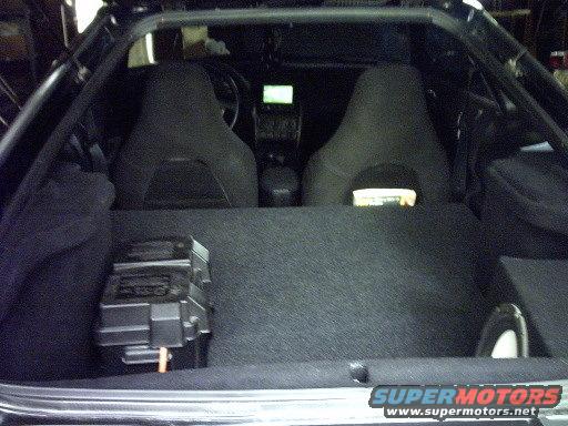 Car interior showing seats, dashboard, and cargo area with a fuse box