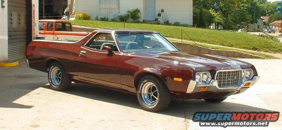 Maroon 1972 Ford Ranchero parked outside a garage with an orange pickup truck inside