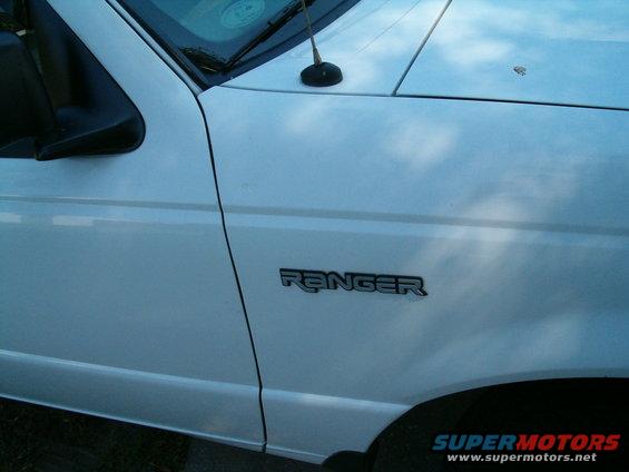 White vehicle fender with black 'RANGER' emblem and side mirror