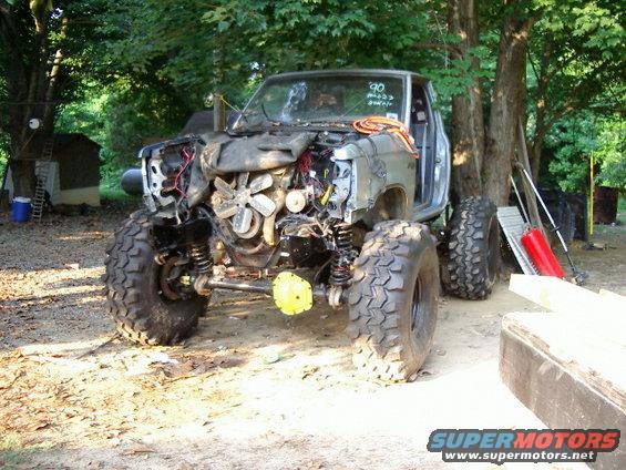 Off-road truck with front end removed, showing engine and suspension. Big tires are mounted