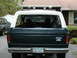 1979 Ford Bronco - Rear view of a dark green SUV with a white hardtop, parked next to another vehicle.