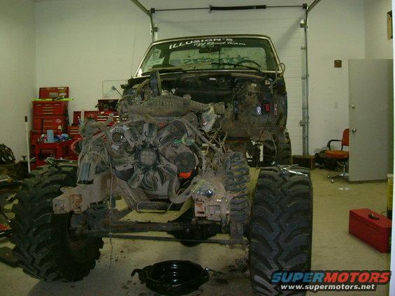Front view of a truck with its engine exposed, undergoing repairs