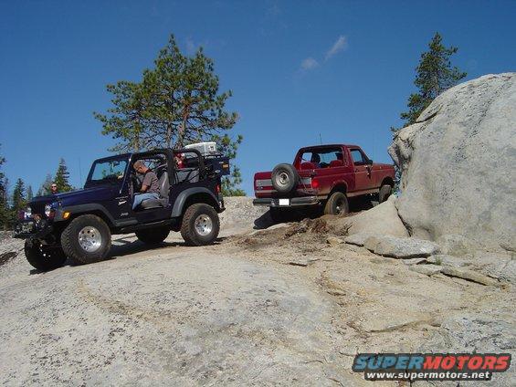 Red 1989 Ford Bronco climbing rocky terrain