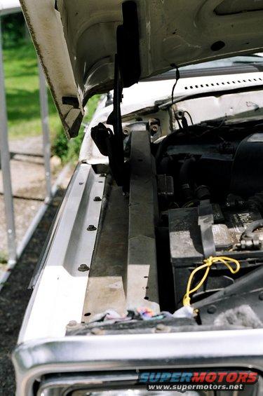 White vehicle engine bay with battery and radiator support