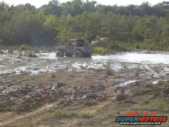 Off-road vehicle stuck in mud, another vehicle visible in background
