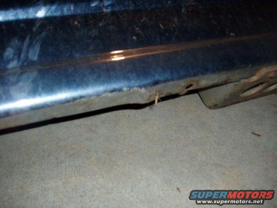 Dark blue vehicle undercarriage with rust and damage
