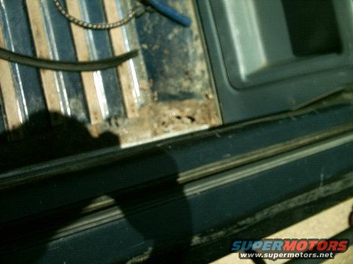 rusted metal panel with debris and a black rubber hose