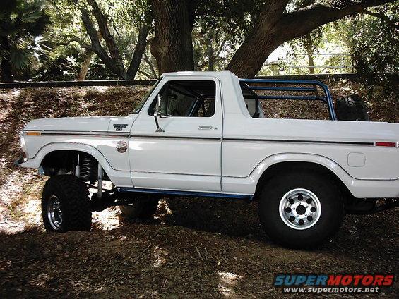 White 1978 Ford Bronco lifted with roll cage, parked outdoors