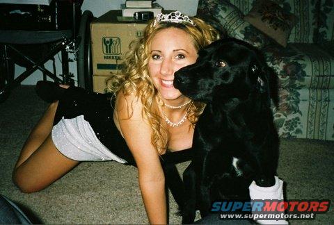 Woman in a tiara and black dress with a black dog, lying on carpet indoors