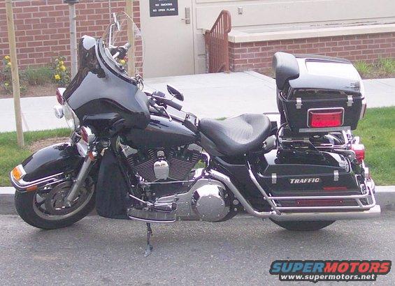 2004 Harley-Davidson FLHTP Police motorcycle parked on pavement, side view. It has a large fairing, windshield, and saddlebags with 'TRAFFIC' text