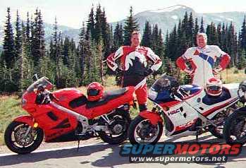 Two sportbikes parked with two riders standing behind them in a mountainous, forested area