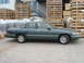 1996 Ford Crown Victoria - Side profile of a green sedan parked outdoors, with industrial crates and building in the background.