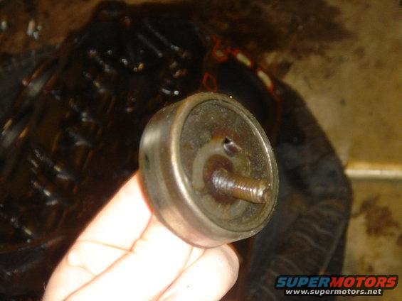 hand holding a metal automotive part with a threaded bolt